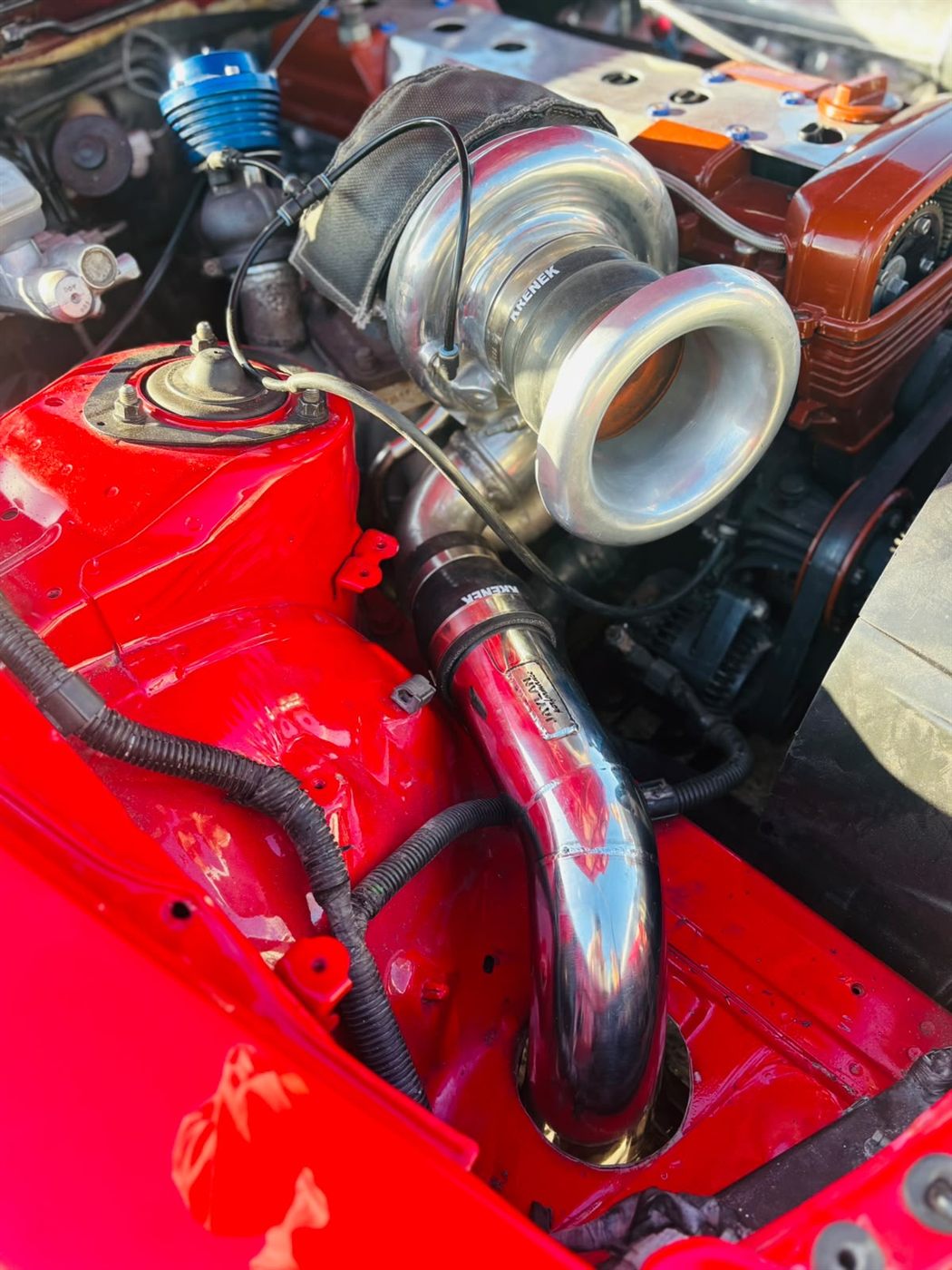 Turbo and intake piping in a red engine bay